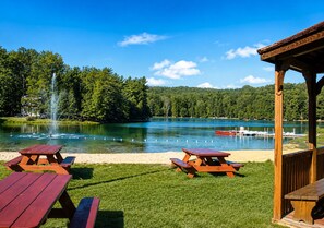 Un área de picnic junto al lago con mesas, un pabellón y un muelle.