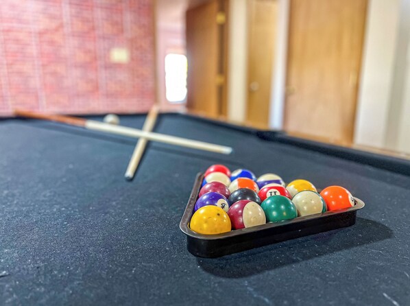 A pool table with a set of billiard balls and a cue stick.
