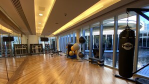 A spacious gym with wooden floors, exercise equipment, and large windows offering views of the outside. - SuperHost - Address Dubai Mall - Gorgeous One Bedroom (Dubai)