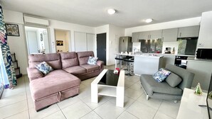 Un salon moderne avec un canapé, une table basse et un fauteuil gris.