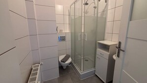 A modern bathroom with a glass shower enclosure, a toilet, and a built-in cabinet. - New flat for 9 ★Special price per month ★ 4 Rooms (Zeitz)
