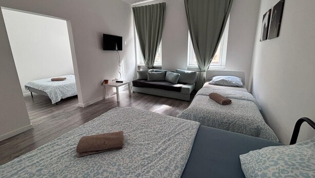 A modern hotel room with two single beds, a sofa, a TV, and a small table. - New flat for 9 ★Special price per month ★ 4 Rooms (Zeitz)