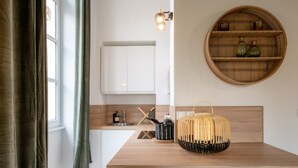 A modern kitchen with a wooden countertop, a round bamboo shelf, and a hanging light fixture.