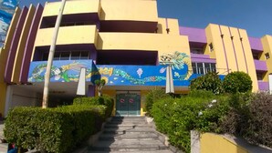 A multi-story building with a colorful facade, a central entrance with steps, and a dragon mural on the wall. - Hotel Coacalco (Coacalco de Berriozábal)