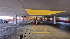 A parking garage with a white car parked near a 'No Pate' sign, yellow directional arrows on the floor, and a 'Circulacion' sign. - Hotel Coacalco (Coacalco de Berriozábal)