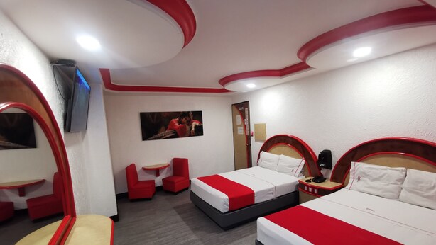 A hotel room with two beds, a small table, two chairs, a TV, and a door with the number 201. - Hotel Coacalco (Coacalco de Berriozábal)
