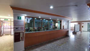 A reception area with a counter, glass windows, and various signs including a Wi-Fi symbol. - Hotel Coacalco (Coacalco de Berriozábal)