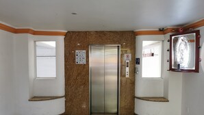 An elevator in a lobby with marble walls and a tiled floor. - Hotel Coacalco (Coacalco de Berriozábal)