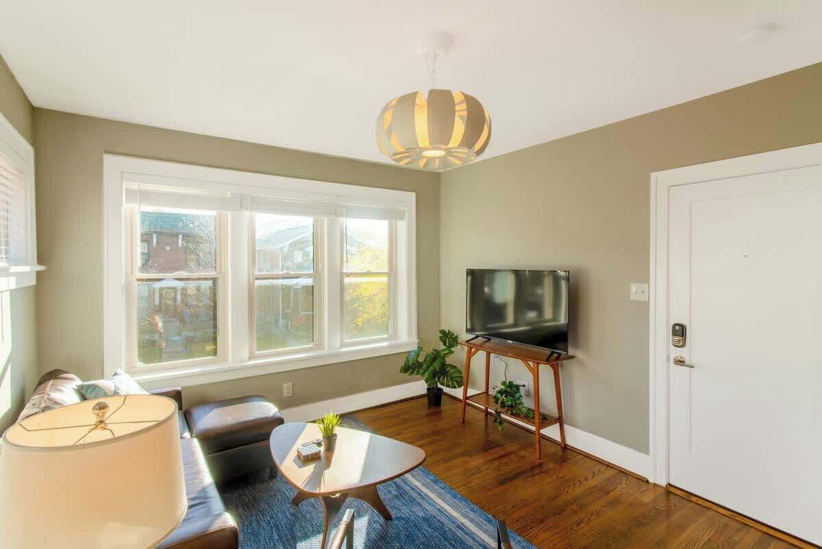 Een woonkamer met een bank, een salontafel, een tv op een dressoir en een groot raam.