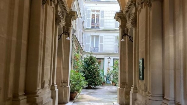Ein Korridor mit klassischer Architektur, darunter Säulen und eine gewölbte Decke.