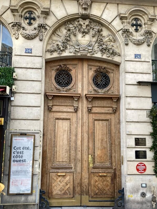 Uma porta dupla de madeira com esculturas detalhadas e uma placa acima.