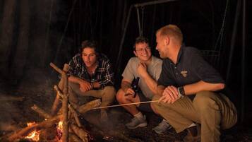 Three people sitting by a campfire at night.