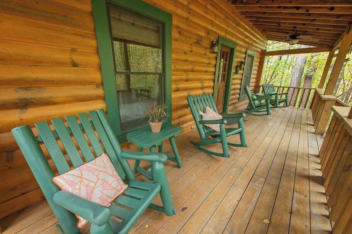 A log cabin with a porch featuring rocking chairs and a table.