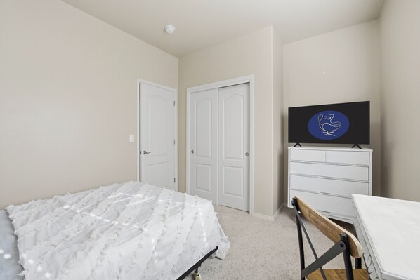 A bedroom with a bed, a dresser, and a television on a dresser.