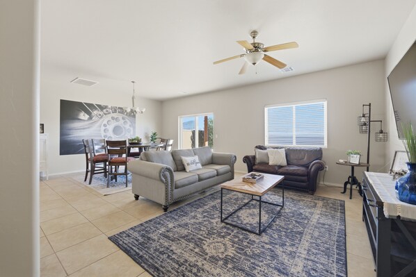 A spacious living room with a ceiling fan, a coffee table, and a dining area with chairs and a table.
