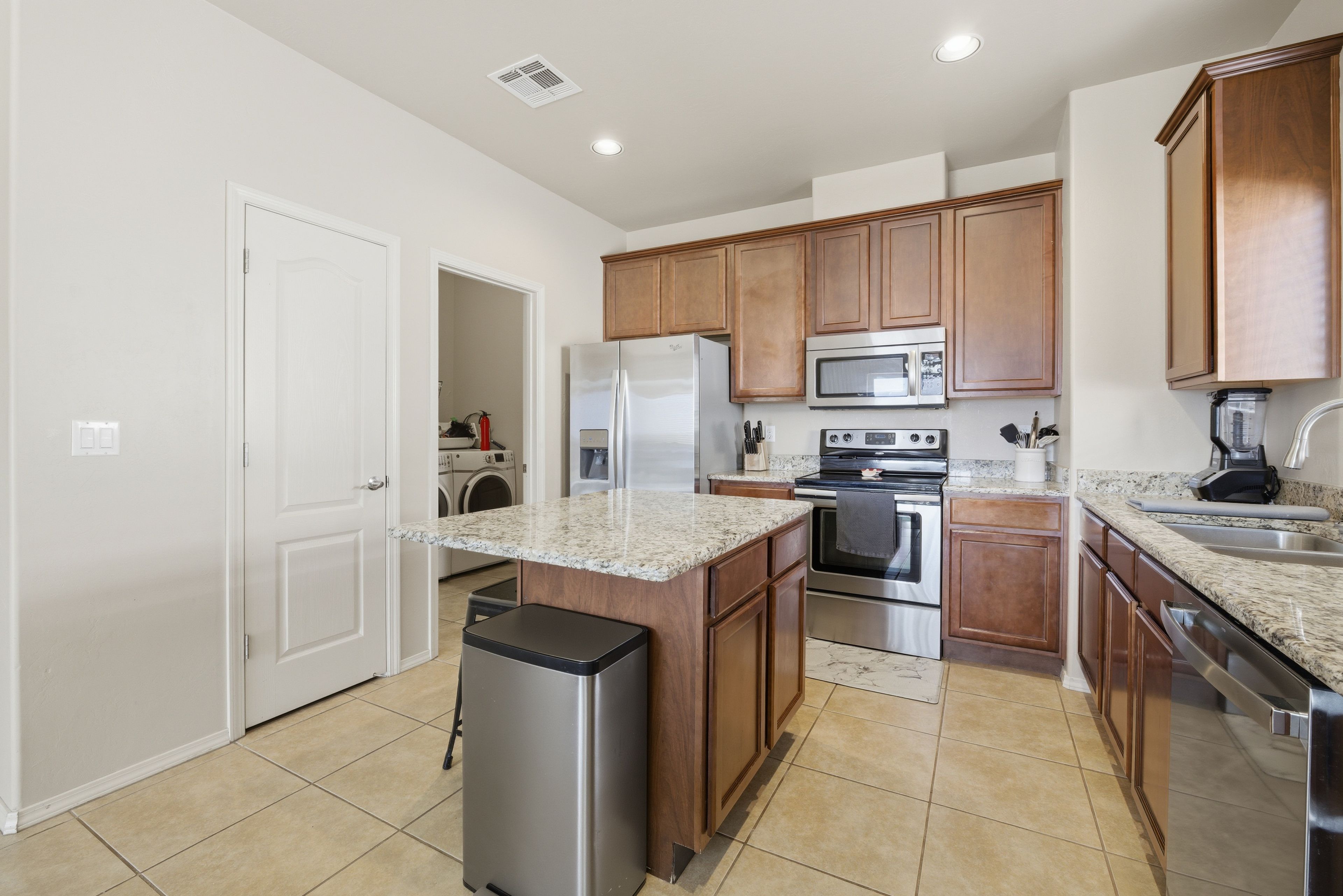 A modern kitchen with wooden cabinets, stainless steel appliances, and a granite countertop.