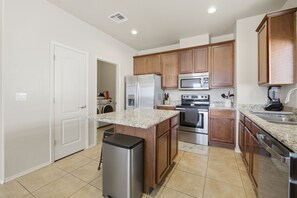A modern kitchen with wooden cabinets, stainless steel appliances, and a granite countertop.