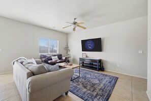 Un salon avec un canapé, une table basse et un téléviseur fixé au mur.