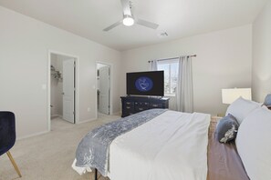 Une chambre à coucher avec un lit, une commode, un téléviseur et un ventilateur de plafond.
