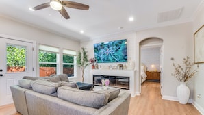 A living room with a grey sofa, a fireplace, and a TV mounted on the wall.