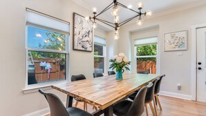 A dining area with a wooden table, black chairs, a chandelier, and artwork on the walls.