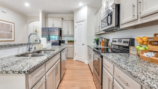 A modern kitchen with granite countertops, stainless steel appliances, and white cabinetry.