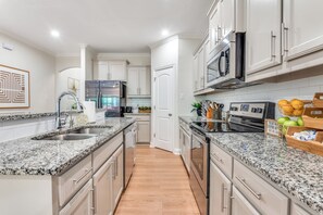 A modern kitchen with granite countertops, stainless steel appliances, and white cabinetry.