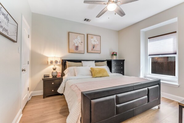 A bedroom with a bed, nightstand, lamp, and two framed pictures on the wall.