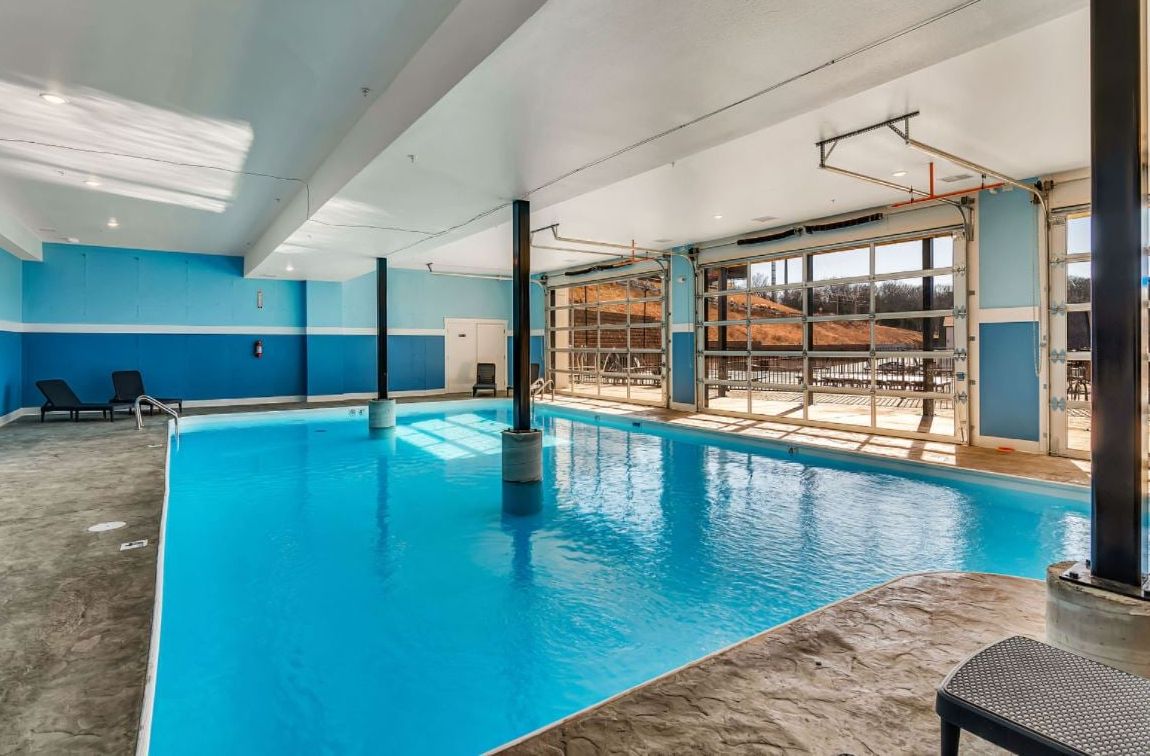 Una piscina interior con agua azul cristalina, rodeada por una decoración en tonos azul y blanco, y vistas a un paisaje nevado a través de amplias ventanas.