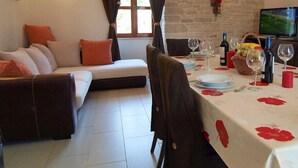 A dining area with a table set for two, a sofa, and a television in the background. - Cottage for 6 persons in Bale near Rovinj (Bale)