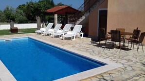 En swimmingpool med hvide liggestole og et bord med stole.