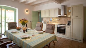 Una cucina con mobili in legno, un tavolo da pranzo apparecchiato con piatti e bicchieri, e un vaso con fiori.