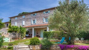 Una casa in pietra con tetto in tegole, un portico coperto e un giardino con delle scale che conducono all'ingresso.