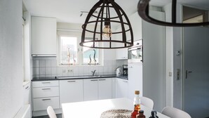 A modern kitchen with white cabinets, a white countertop, and a hanging light fixture. - Vacation home 114 in villa park the oyster bay (Wemeldinge)