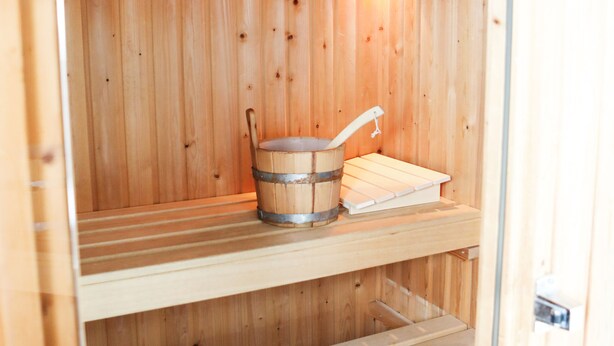 A wooden sauna with a bench, a bucket, and a shelf. - Vacation home 114 in villa park the oyster bay (Wemeldinge)
