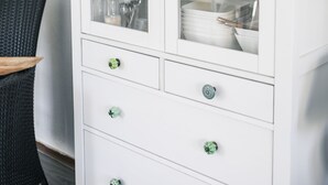 A white cabinet with glass doors, containing plates, bowls, and glassware. - Vacation home 114 in villa park the oyster bay (Wemeldinge)