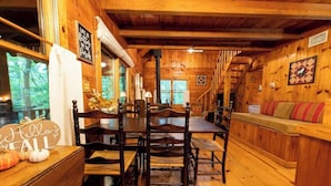 Un intérieur en bois comprenant une table à manger, des chaises, un canapé et une cheminée.