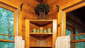 Un intérieur en bois avec une étagère centrale où sont disposés des verres, des assiettes et des bols.
