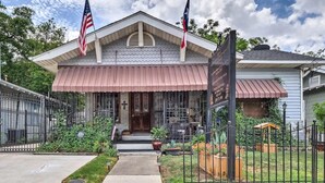 A two-story building with a red awning, a front porch, and a small garden area.