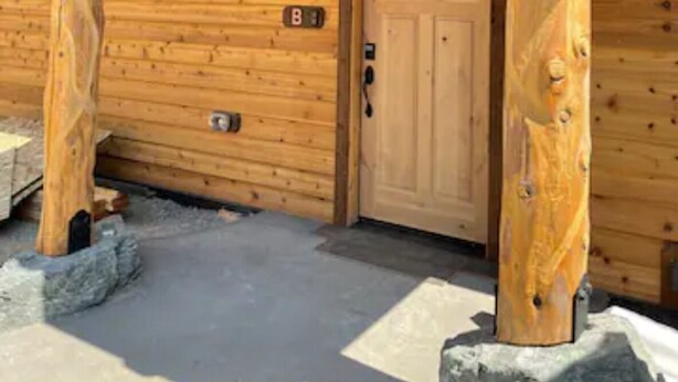 A wooden cabin with a wooden door marked with the number 8, a small porch with wooden beams, and a stone foundation. - Cedar Mountain - Suite B (Grants Pass)