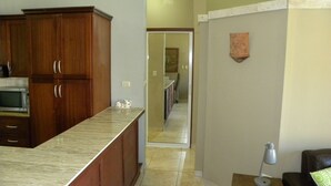 Cucina con mobili in legno, piano di lavoro in marmo e forno a microonde.