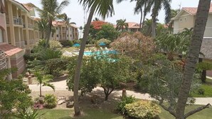 Cortile di un resort con piscina, palme e prato curato.