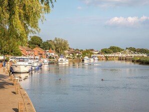 A riverside view with boats docked, a pedestrian path, and houses in the background. - 2 bedroom accommodation in Reedham (Reedham)