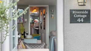 A cozy entrance with a sign reading 'Riverside Cottage 44,' a dining area with a table set for two, and a staircase leading to the upper floor. - 2 bedroom accommodation in Reedham (Reedham)