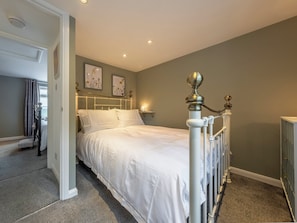 Une chambre avec un lit blanc, un radiateur, une table de chevet et une lampe fixée au mur.