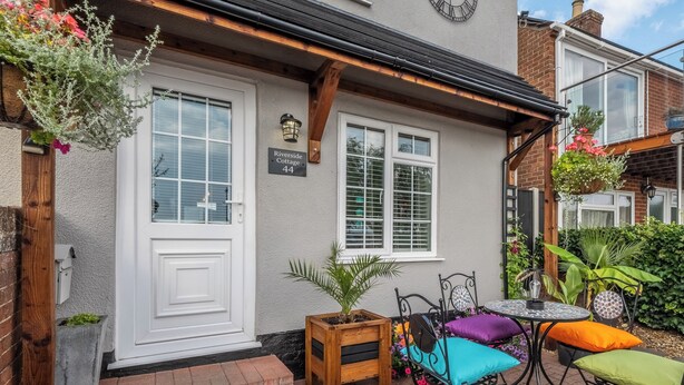 A house with a white door, a small porch with a table and chairs, and a sign reading 'Riverside Cottage 44'. - 2 bedroom accommodation in Reedham (Reedham)