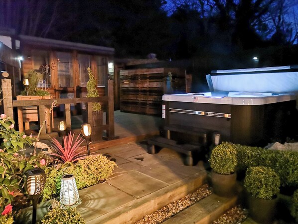 Un bain à remous dans un jardin agrémenté de structures en bois et de plantes en pot.