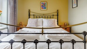 A neatly made bed with patterned pillows, a bedside table with a lamp, and a framed picture on the wall. - 2 bedroom accommodation in Reedham (Reedham)