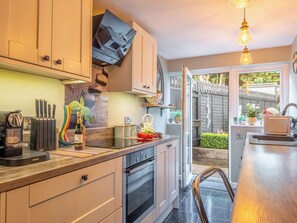 A modern kitchen with a built-in oven, a coffee machine, and a large window overlooking a garden. - 2 bedroom accommodation in Reedham (Reedham)
