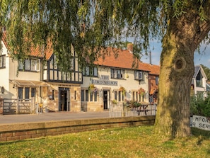 Un pub traditionnel appelé « The Lord Nelson », avec une façade classique, une entrée bien visible et un arbre au premier plan.